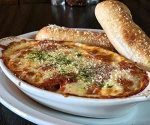 Baked Spaghetti with two fresh breadsticks.