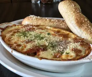 Baked Spaghetti with two fresh breadsticks.